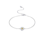 Silver anklet with a daisy charm on a person's ankle against a white background