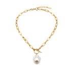 Gold chain necklace with a pearl pendant worn by a person in a white shirt.