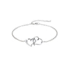 Silver anklet with interlocking heart charms on a person's ankle, with flowers in the background.